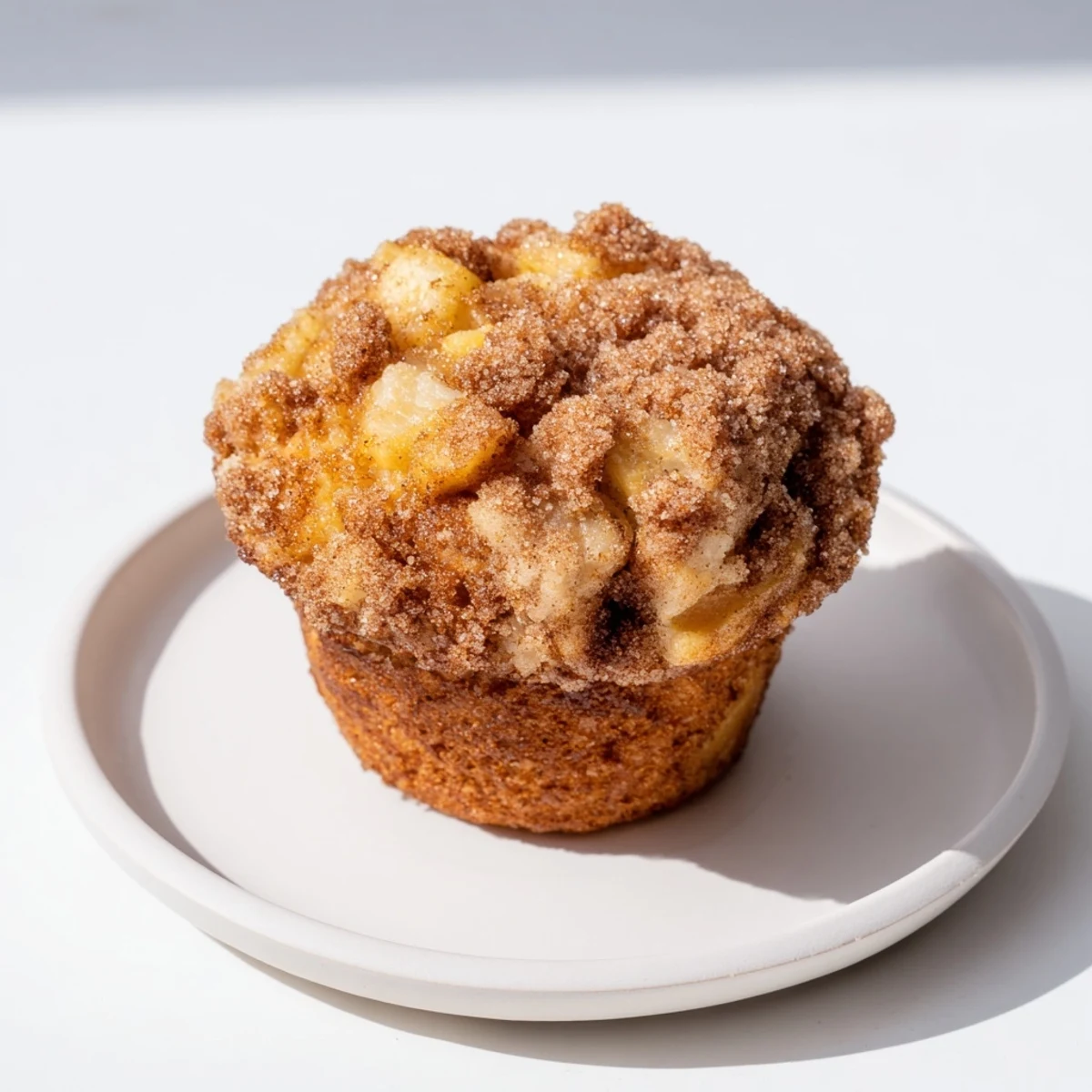 Golden-brown cinnamon apple muffins, warm from the oven, with a crunchy sugar topping.
