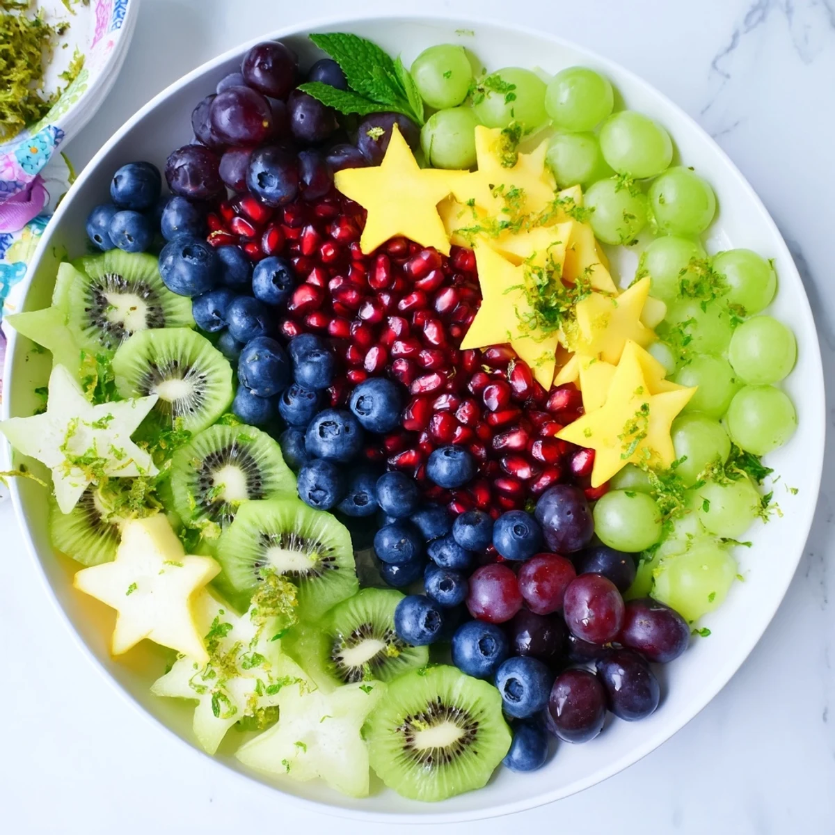A beautiful Pomegranate and Mint Star Fruit Platter showcases juicy seeds alongside starfruit slices, ready to serve and enjoy.