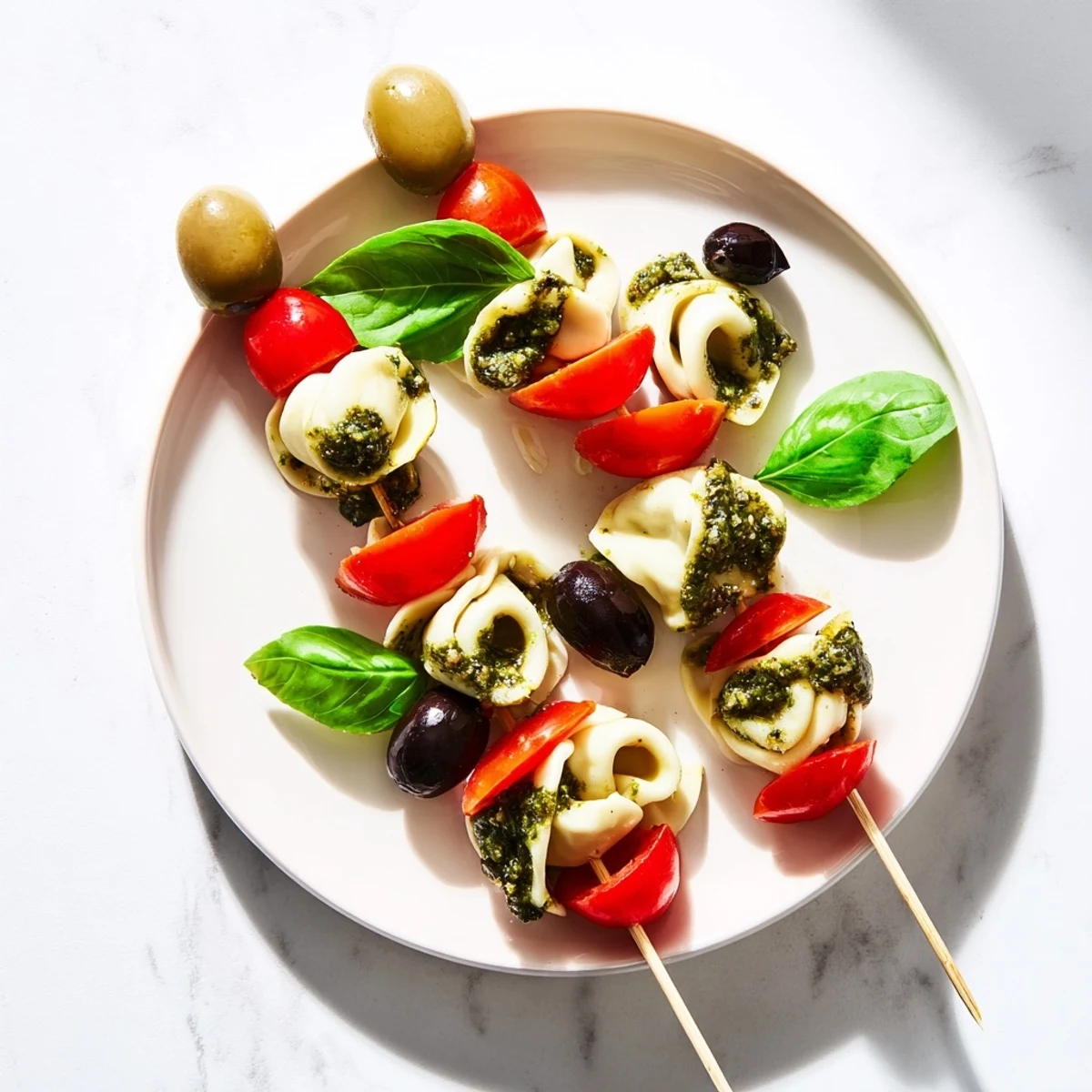 Appetizer Skewers: colorful tortellini, pesto, and olives arranged artfully and ready to serve at a party.