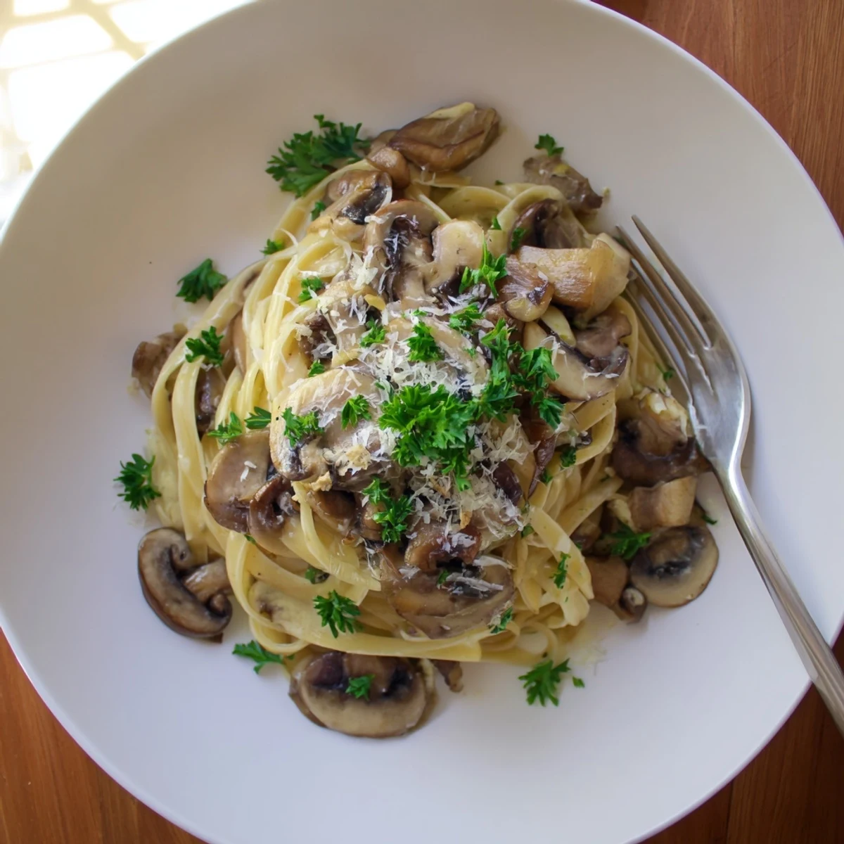 Fork-tossed Creamy Mushroom Linguine with mixed mushrooms in a light cream sauce, served alongside a crisp green salad.