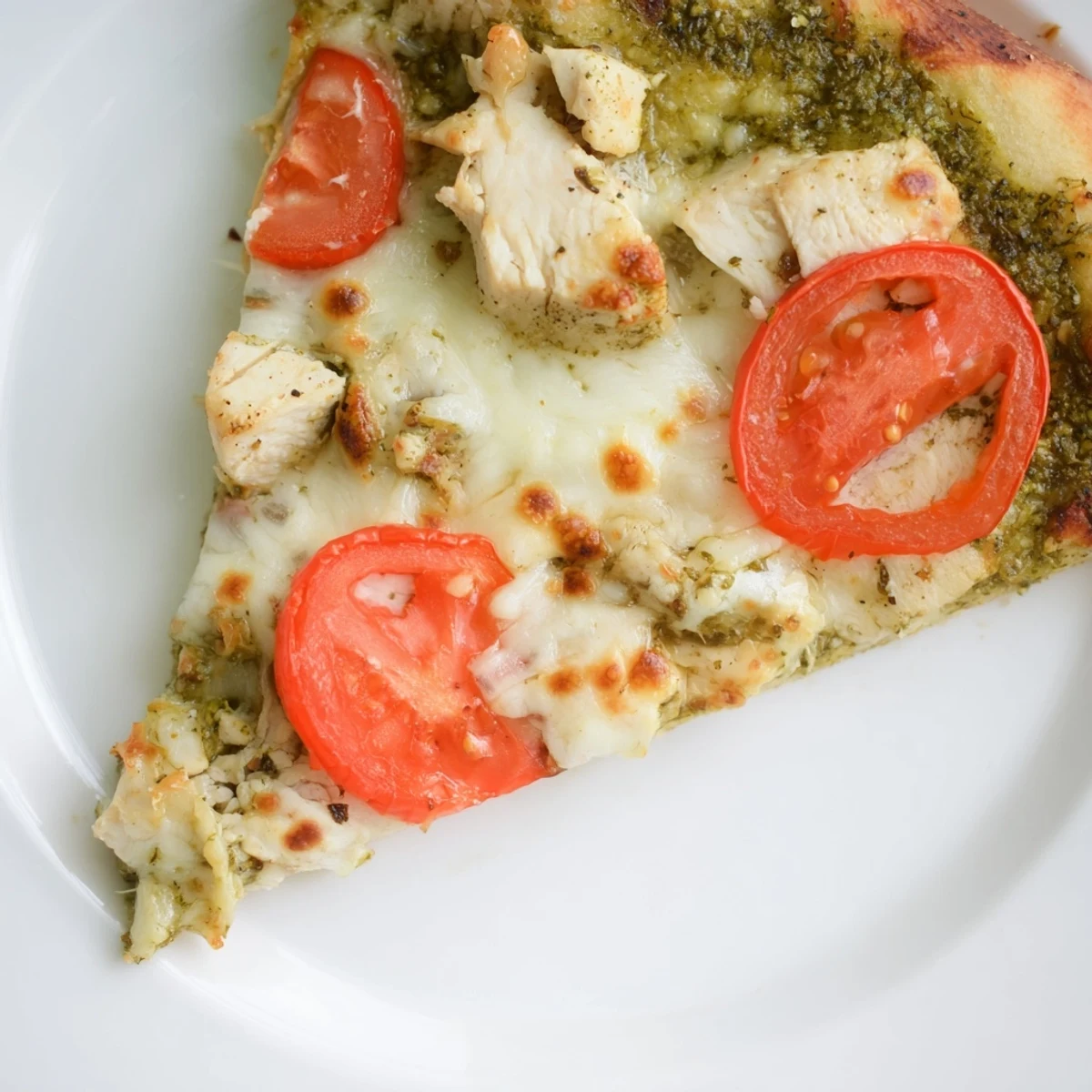 Golden-brown thin-crust Chicken Pesto Pizza topped with melted mozzarella, fresh tomato slices, and a drizzle of basil pesto.