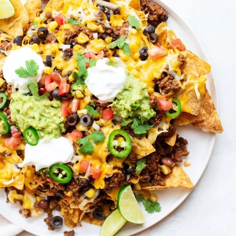Loaded Nachos with Beef and Cheese topped with sour cream, guacamole, and fresh cilantro.  