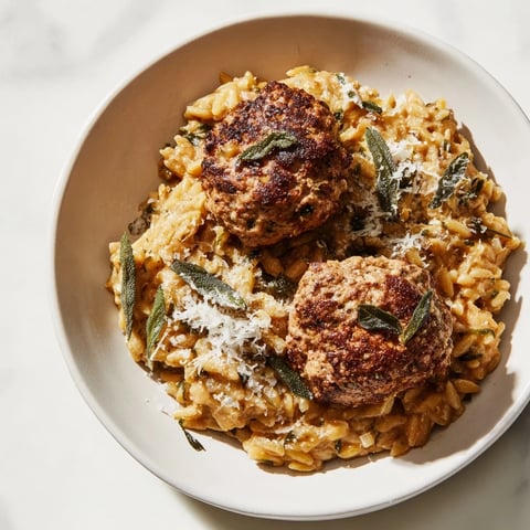 Warm, rustic sage turkey meatballs nestled in vibrant pumpkin orzo, ready for a comforting meal.