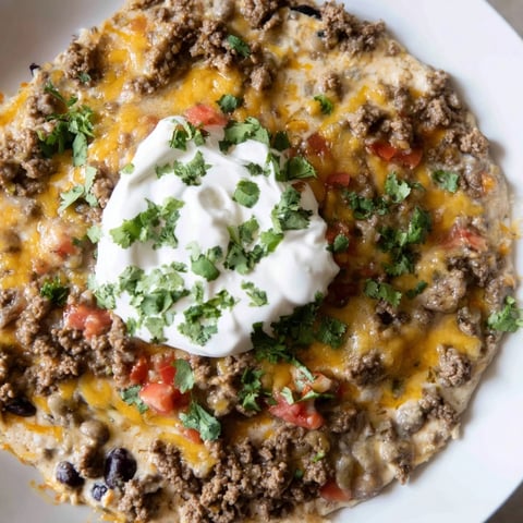 Warm, bubbling Slow Cooker Cream Cheese Taco Dip with a vibrant swirl of cool, creamy sour cream and cilantro.