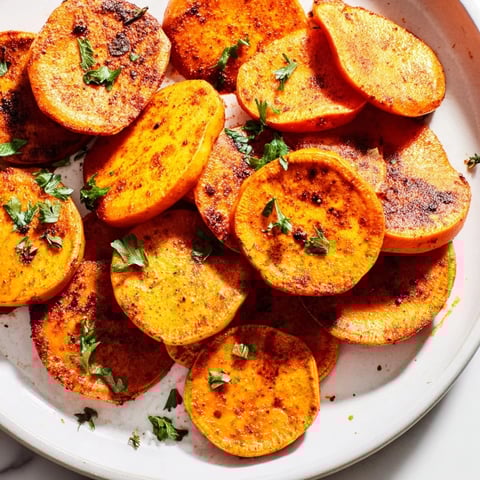 Golden brown Cajun roasted sweet potatoes, crispy edges, offering a smoky and savory flavor.
