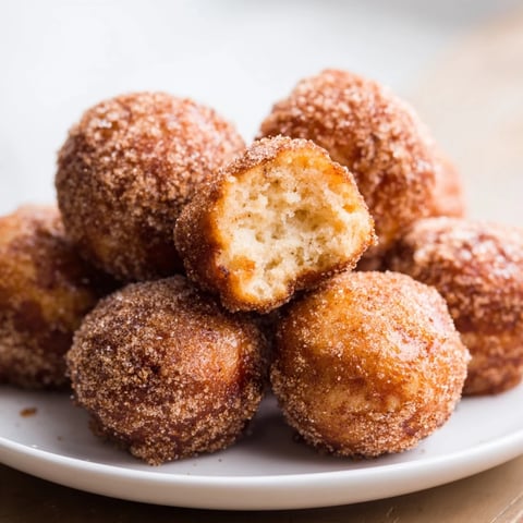 Warm, golden air fryer cinnamon donuts, freshly coated in cinnamon sugar, ready to eat.