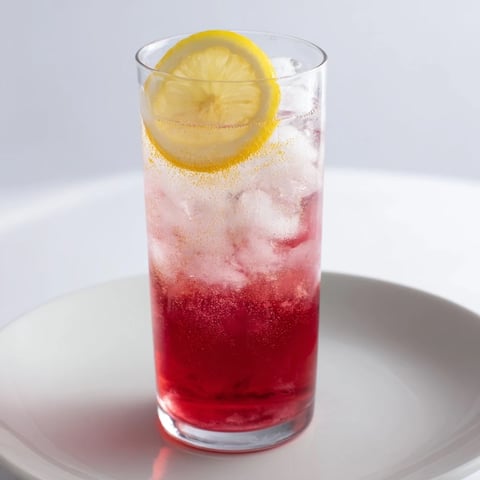 A refreshing Sleepy Girl Mocktail with a deep red hue, garnished with a bright lemon slice.