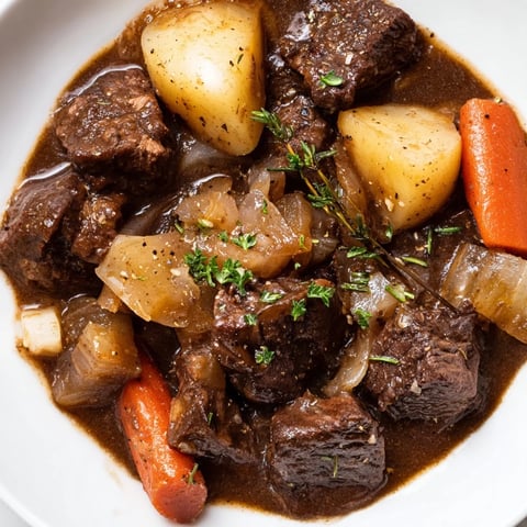Steaming Irish Beef Stew with tender beef, carrots, and potatoes, a hearty meal for cold evenings.