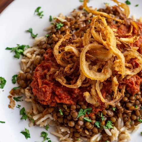 Golden-brown crispy onions crown a delicious bowl of homemade Egyptian Koshari, a flavorful vegan meal.