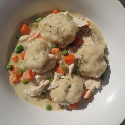Golden-brown dumplings sit atop a bubbling Chicken and Dumplings Casserole, ready to be enjoyed.