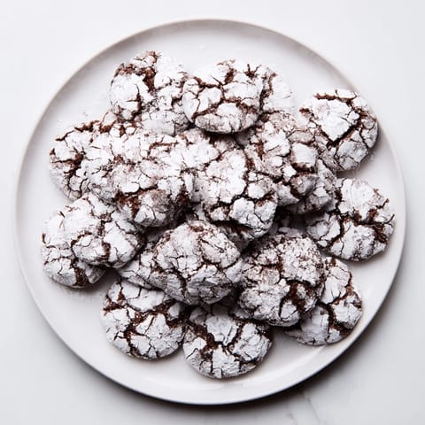 Warm, crackled Chocolate Crinkle Cookies on a baking sheet, with a soft, chewy texture.