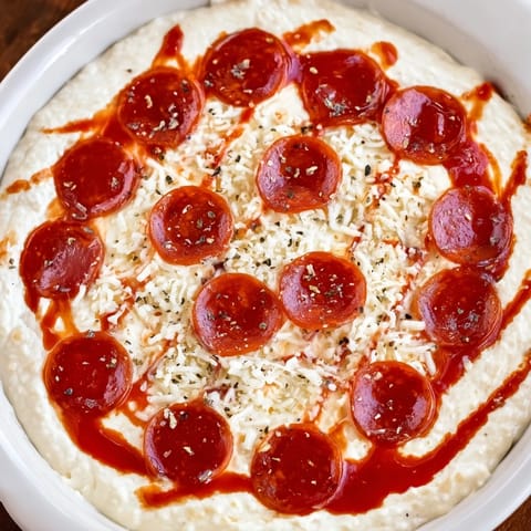 A bubbly, cheesy Pizza Dip topped with pepperoni, served with crispy bread for dipping.