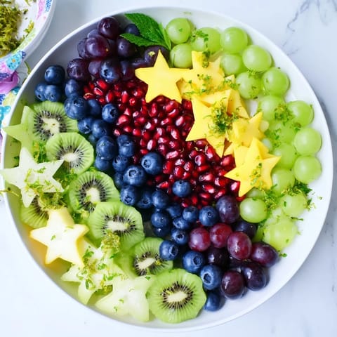 A beautiful Pomegranate and Mint Star Fruit Platter showcases juicy seeds alongside starfruit slices, ready to serve and enjoy.