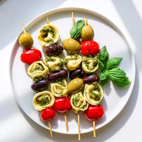 Vivid Appetizer Skewers showcasing pesto-coated tortellini, fresh olives, and bright cherry tomatoes, perfect for sharing.