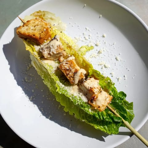 Close-up of Chicken Caesar Salad Skewers: tender chicken and crisp romaine lettuce, drizzled with Caesar dressing.