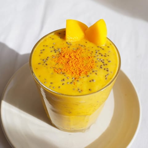A refreshing close-up of a Mango Turmeric Smoothie, expertly garnished with coconut for a tropical feel.