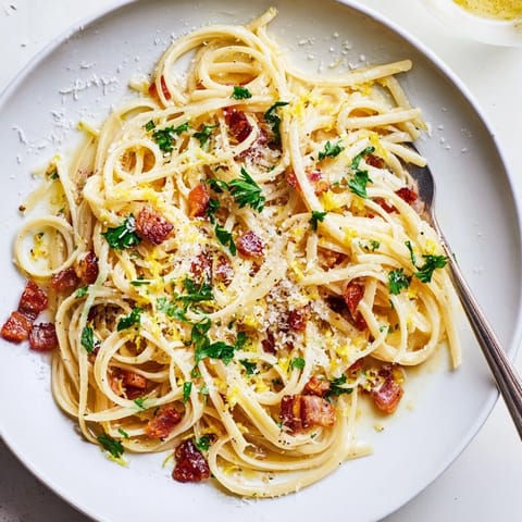 Crispy Bacon Linguine served hot with a sprinkle of Parmesan on a rustic wooden table.