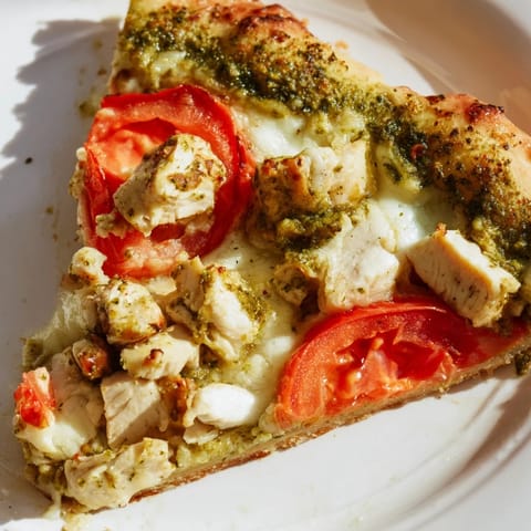 A close-up of a rustic Chicken Pesto Pizza with juicy chicken, vibrant green pesto, and bubbling cheese on a crisp crust.