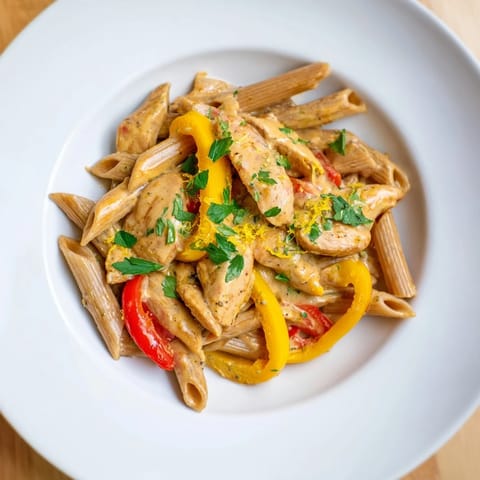 A close-up of creamy Cajun chicken pasta lite, highlighting its rich, spicy sauce clinging to al dente whole wheat penne and tender chicken.