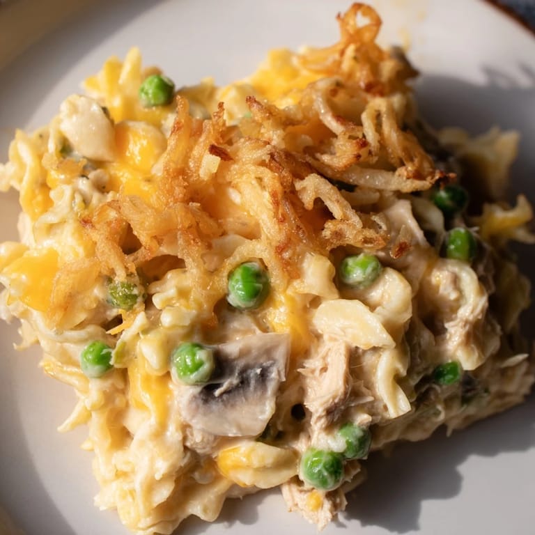 A close-up of creamy, savory Homemade Tuna Noodle Casserole, topped abundantly with crunchy fried onions.