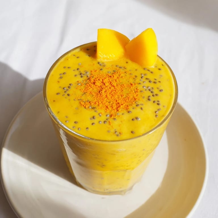 A refreshing close-up of a Mango Turmeric Smoothie, expertly garnished with coconut for a tropical feel.