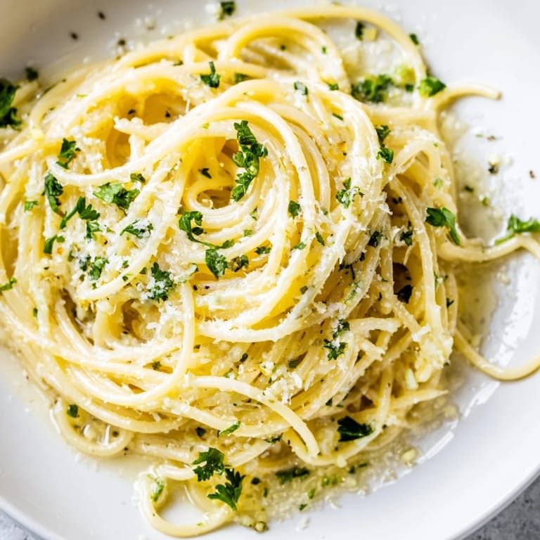 Steam rises from a forkful of Lemon Butter Pasta Light, revealing tender angel hair pasta tossed in a buttery lemon sauce with herbs and freshly ground pepper.
