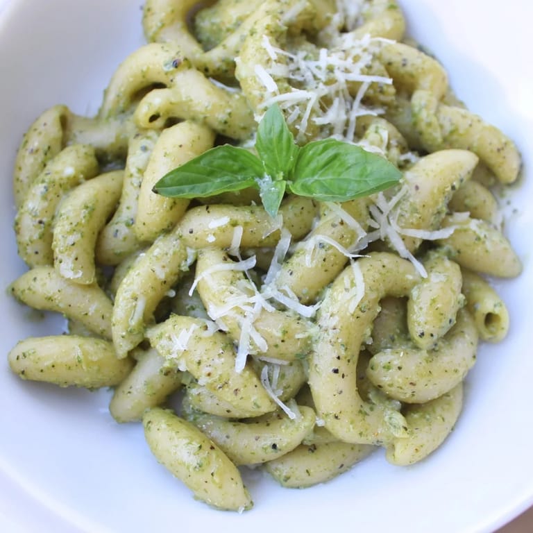 A close-up of creamy avocado pesto mac, showcasing its vibrant color and fresh basil garnish.