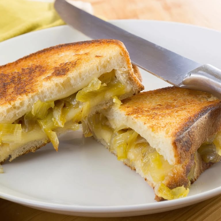 Served warm on a rustic plate, this vegetarian Havarti & Caramelized Leek Grilled Cheese pairs perfectly with tomato soup.