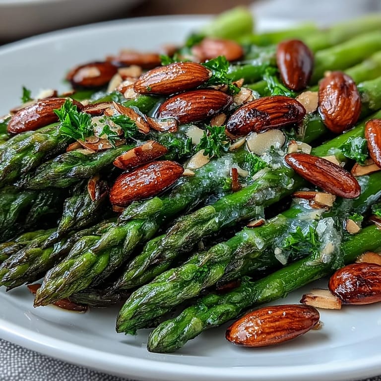 Tender asparagus sautéed in golden butter and brightened with lemon, topped with crisp toasted almonds for a delightful vegetarian side.