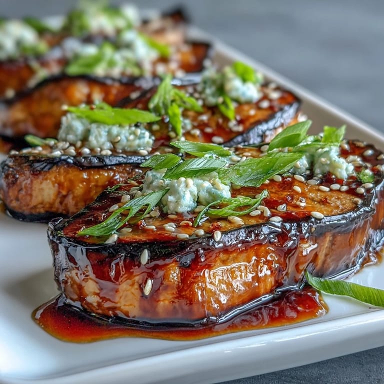 Golden-brown miso-glazed eggplant slices served warm, garnished with sesame seeds and sliced green onions.  