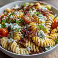 Vibrant Elote Pasta Salad with Cotija, chili, and lime, featuring charred corn and juicy tomatoes tossed in a zesty dressing.